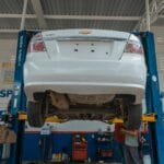 Białe auto na podnośniku w warsztacie podczas naprawy zawieszenia