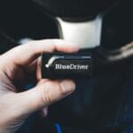 Dłoń trzymająca bezprzewodowy tester diagnostyczny we wnętrzu auta