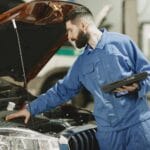 Mechanik w warsztacie sprawdza silnik Renault Kangoo pod otwartą maską