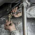 Ręce hydraulika montującego stalowe rury w instalacji kanalizacyjnej
