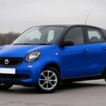 Niebieski miejski hatchback zaparkowany przy ulicy wśród budynków