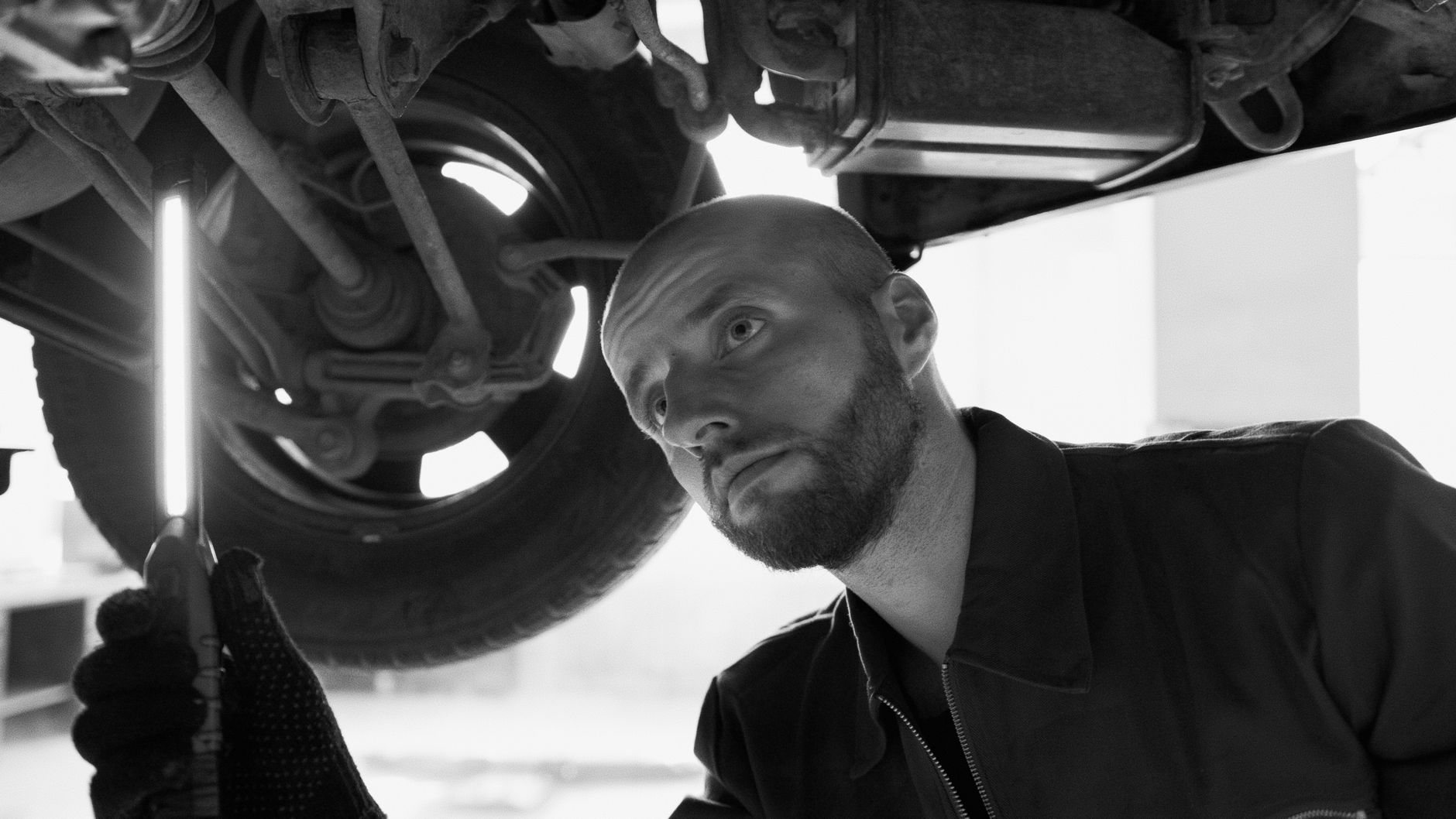 Mechanik z latarką ogląda podwozie auta w warsztacie