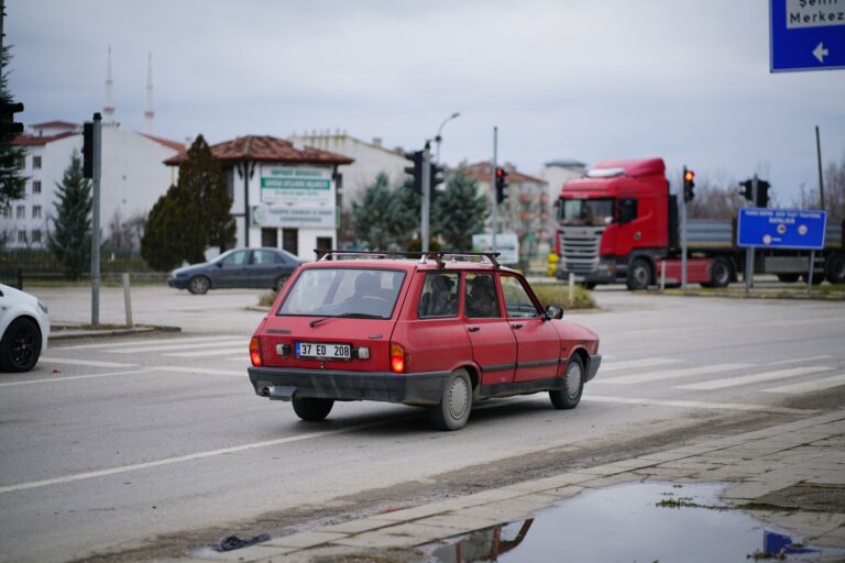 Czerwony zabytkowy samochód na miejskiej ulicy z znakami drogowymi