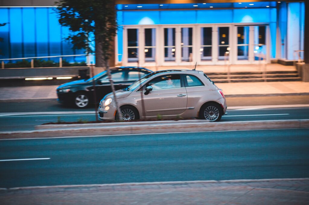 Fiat 500 na miejskiej ulicy obok nowoczesnego podświetlonego budynku